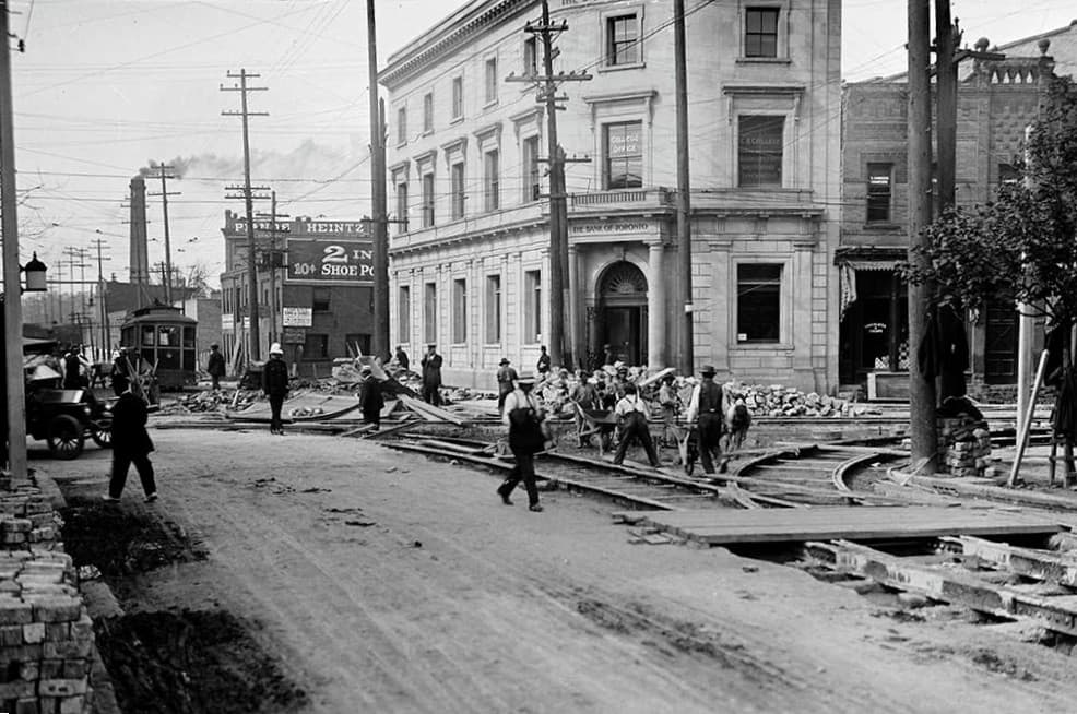 Historical street scene with workers installing streetcar tracks in front of The Bank of Toronto.